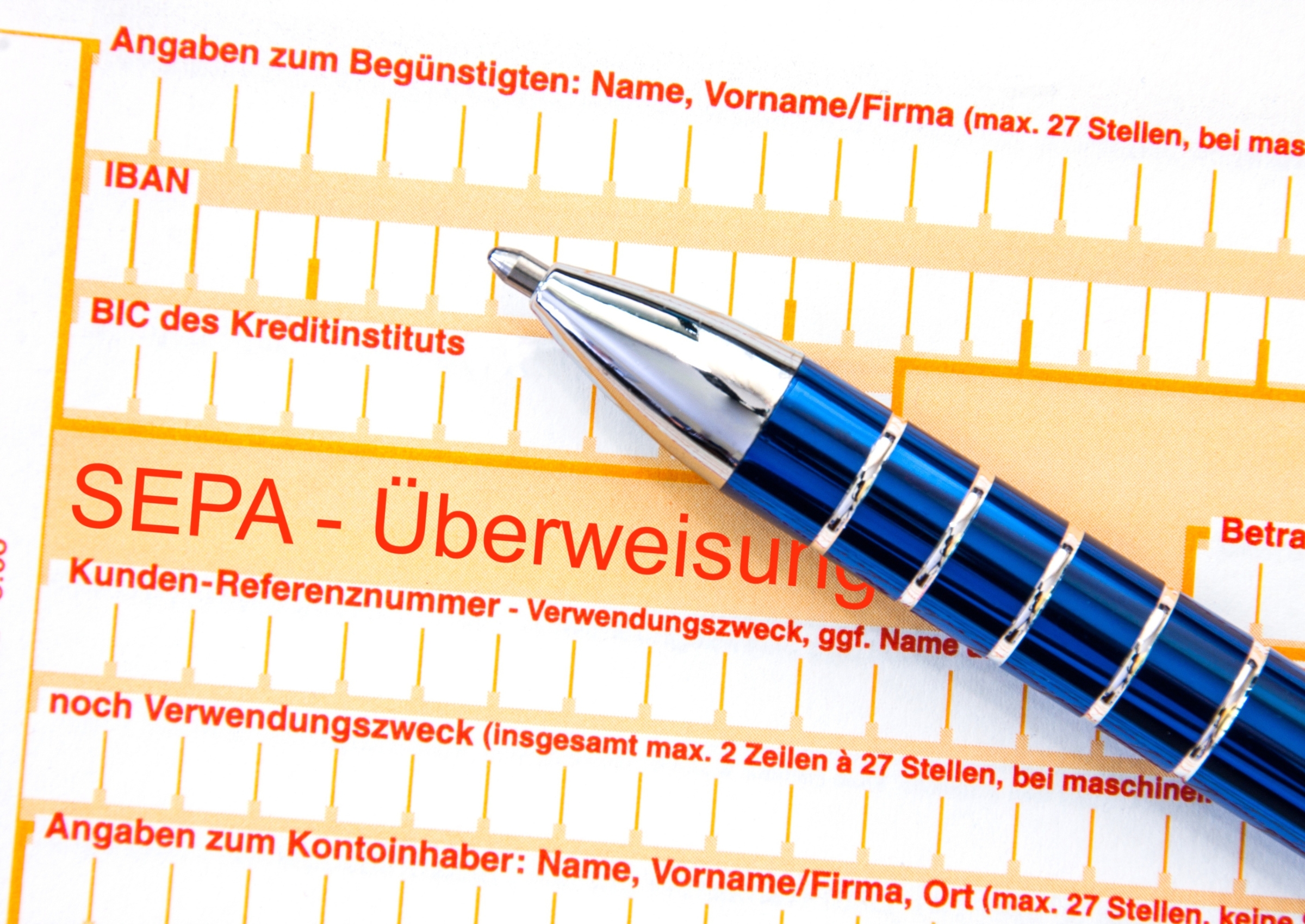 Nahaufnahme eines SEPA-Überweisungsformulars mit einem blauen Kugelschreiber zum Ausfüllen von Bankdaten wie IBAN und BIC